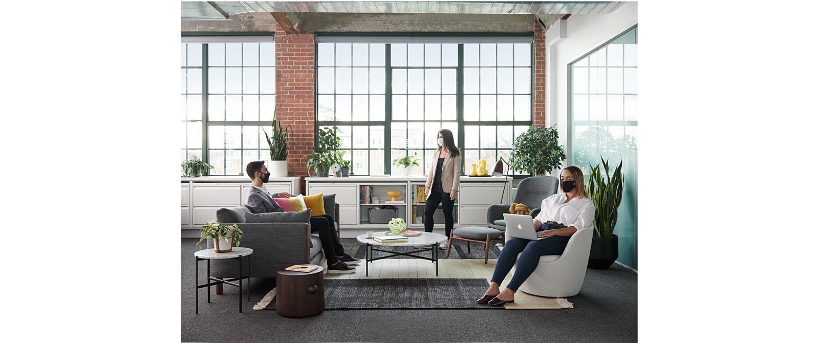 Three people working at chairs and couches in a casual office environment.