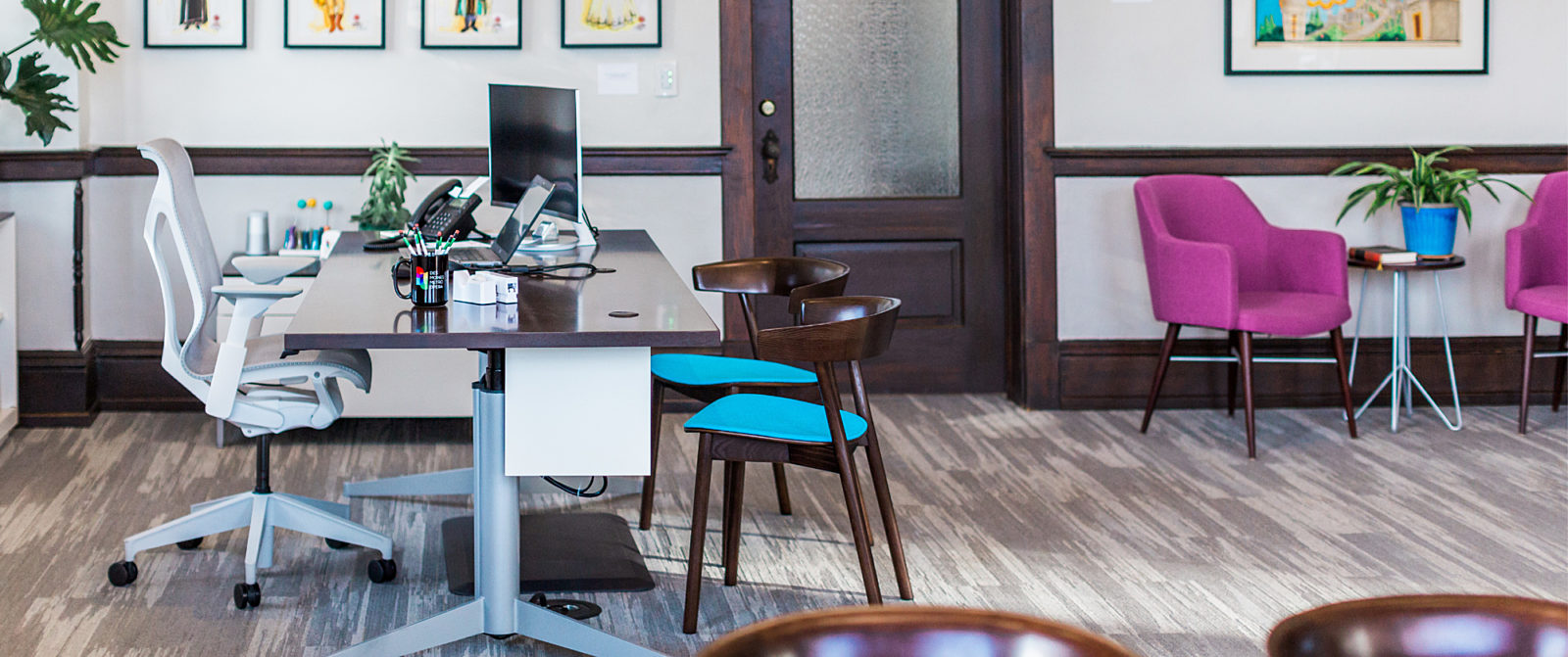 Private office featuring modern office chair, traditional wood architectural elements, and bright finishes on side chairs.