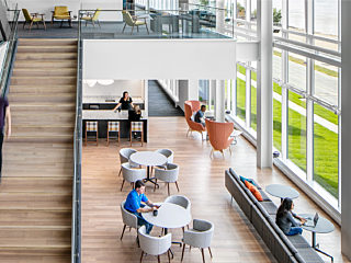 Central atrium of IHMVCU showcasing the central staircase surrounded by modern furniture settings overlooking the Mississippi River.